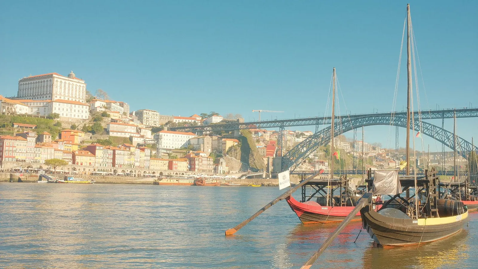 Le pont Dom Luís I et des bateaux rabelo chargés de fûts de vin de Porto sur le Douro, face à la Ribeira